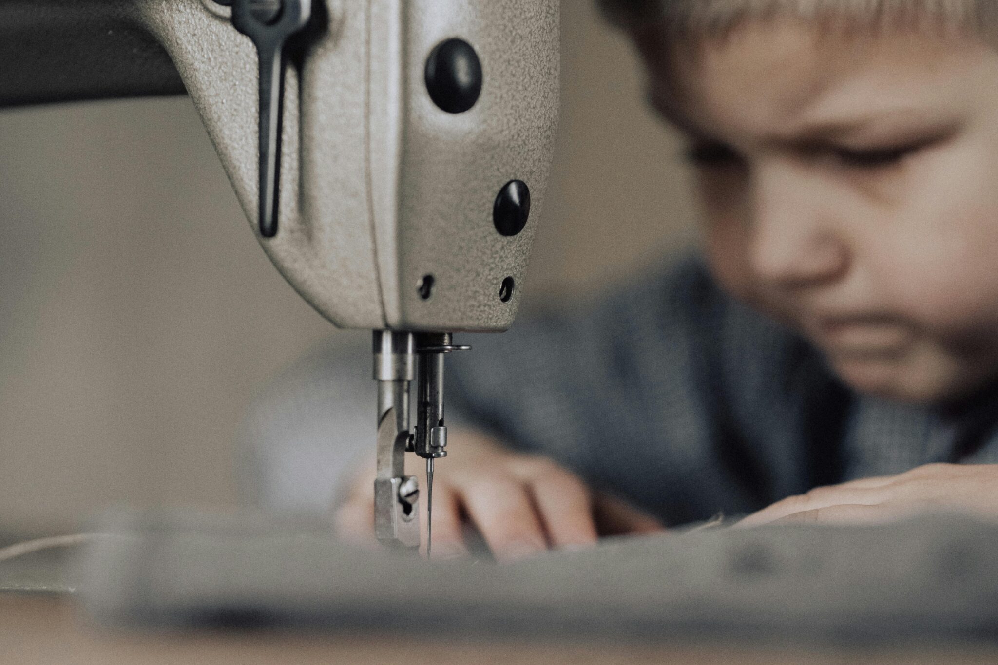 child laboring at industrial sewing machine